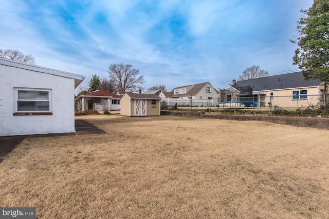 view of yard featuring a shed, fence, and an outbuilding