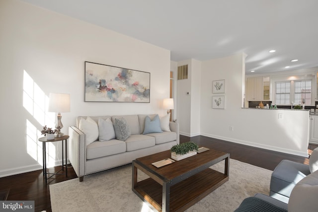 living room with dark wood finished floors, baseboards, visible vents, and a wealth of natural light