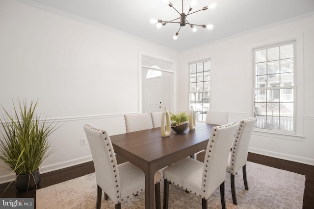 dining space featuring crown molding, a notable chandelier, wood finished floors, and baseboards