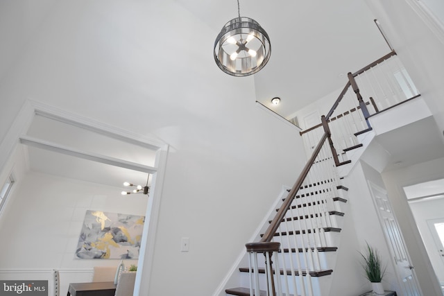 stairway featuring a high ceiling and a notable chandelier