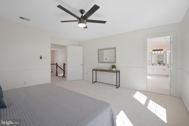 bedroom with connected bathroom, a ceiling fan, visible vents, and light carpet