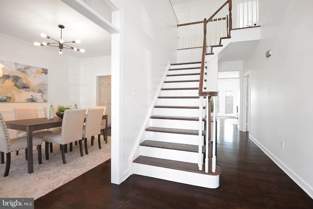 stairway featuring crown molding, a notable chandelier, wood finished floors, and baseboards