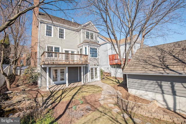 rear view of property featuring a chimney, french doors, a wooden deck, and a fenced backyard