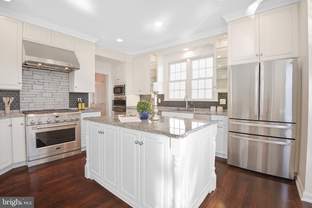 kitchen with a sink, stainless steel appliances, wall chimney exhaust hood, and dark wood finished floors