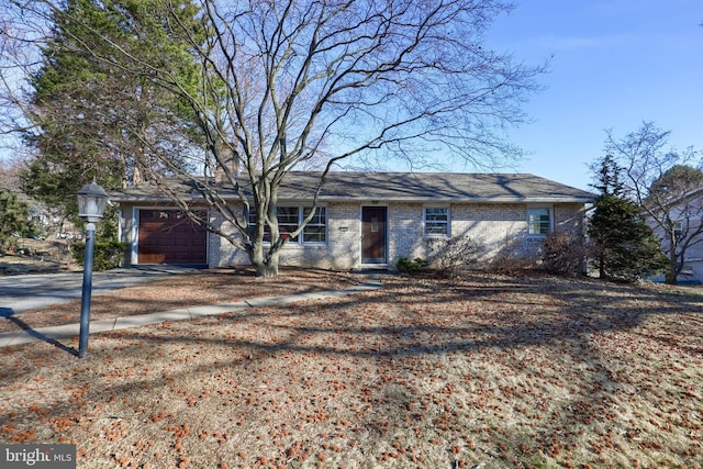 ranch-style home featuring a garage, concrete driveway, and brick siding