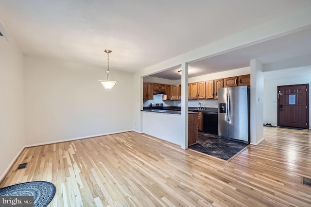 kitchen featuring stainless steel fridge, visible vents, dishwasher, dark countertops, and light wood-type flooring