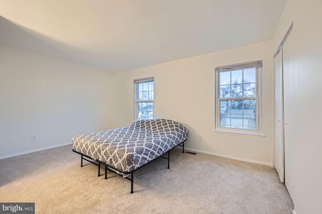 carpeted bedroom with a closet and baseboards