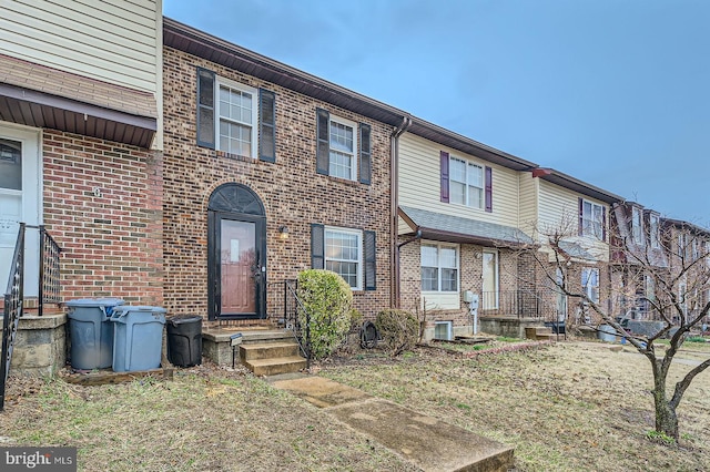 view of property with brick siding and central AC unit