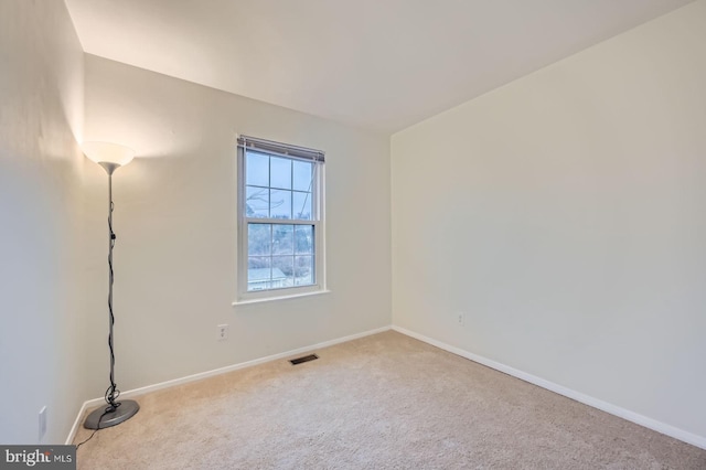 empty room with carpet flooring, visible vents, and baseboards