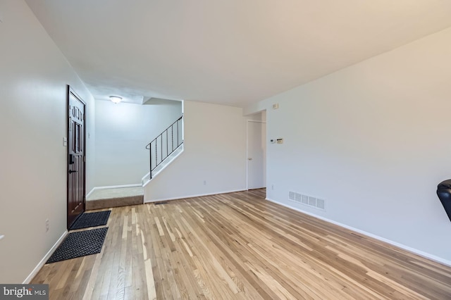 interior space featuring light wood-type flooring, visible vents, stairway, and baseboards