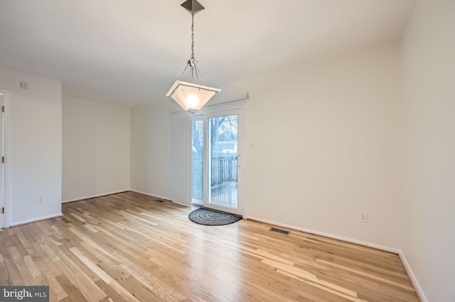 unfurnished dining area with visible vents, light wood-style flooring, and baseboards