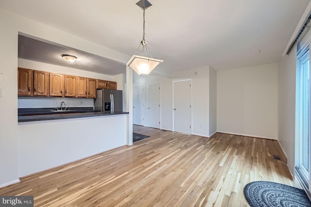 kitchen featuring dark countertops, light wood-style floors, a sink, and stainless steel fridge with ice dispenser