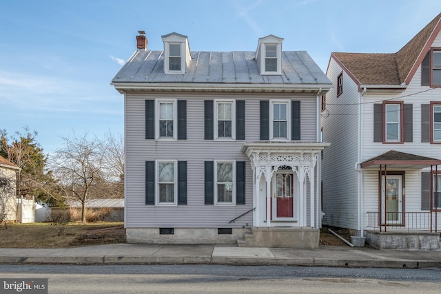 view of front of property with a standing seam roof, a chimney, and metal roof