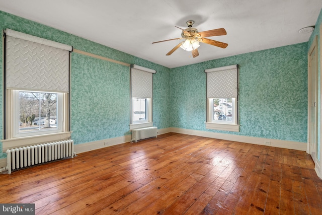 unfurnished room featuring wallpapered walls, hardwood / wood-style flooring, and radiator