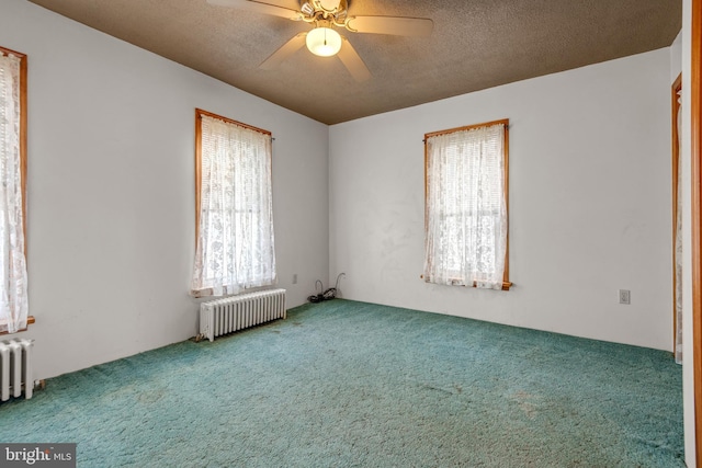 carpeted empty room featuring radiator heating unit, a ceiling fan, and a textured ceiling