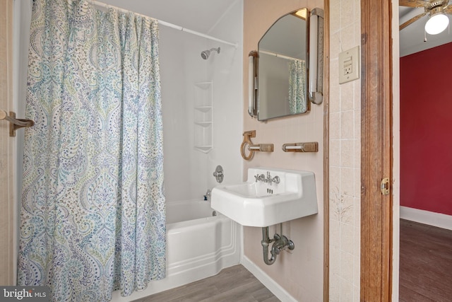 bathroom with baseboards, wood finished floors, and shower / tub combo with curtain