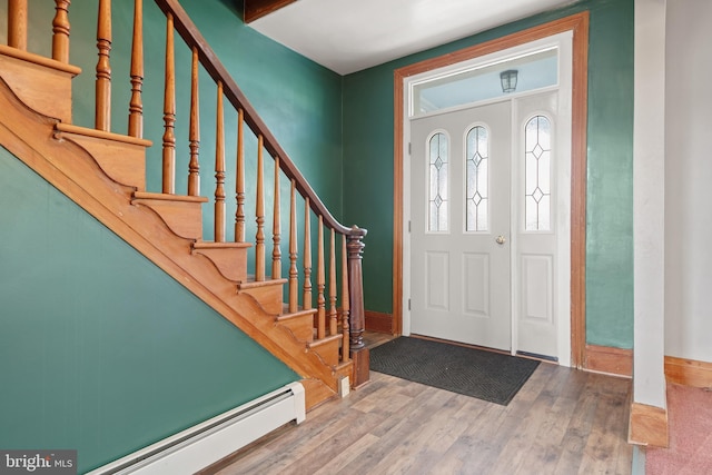 foyer with stairway, baseboard heating, and wood finished floors