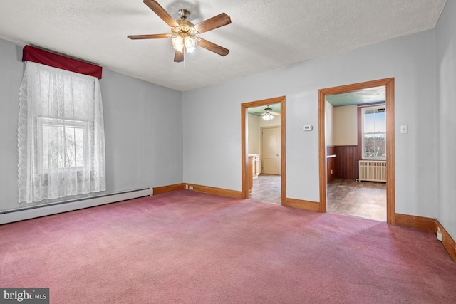 spare room featuring a baseboard heating unit, radiator, carpet flooring, and a textured ceiling