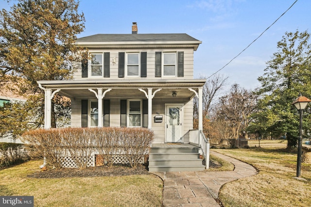 traditional style home featuring covered porch, a chimney, and a front yard