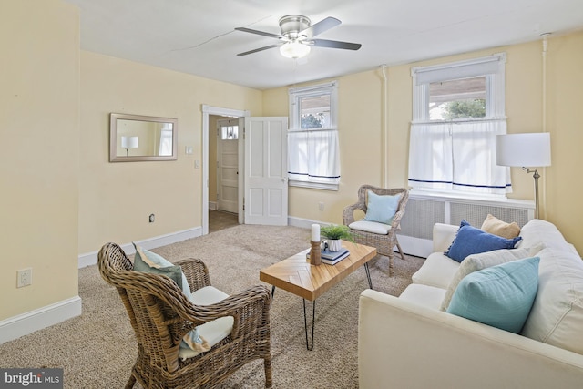 carpeted living area with baseboards and a ceiling fan