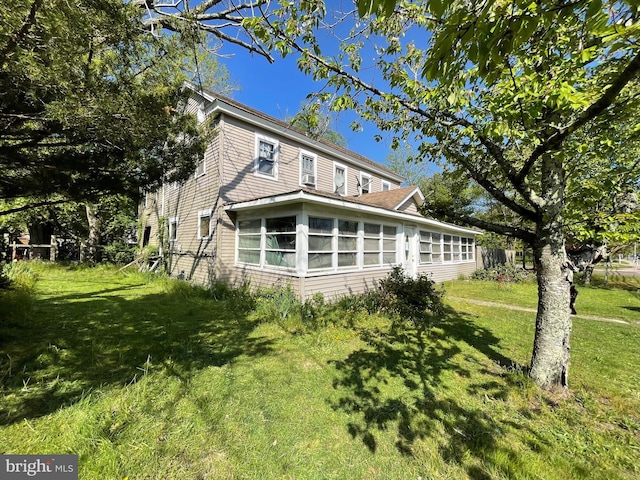 view of side of property featuring a yard and a sunroom