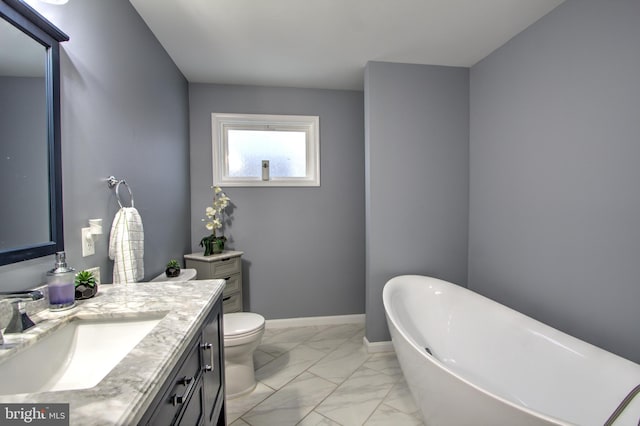 full bathroom with baseboards, toilet, marble finish floor, a freestanding bath, and vanity