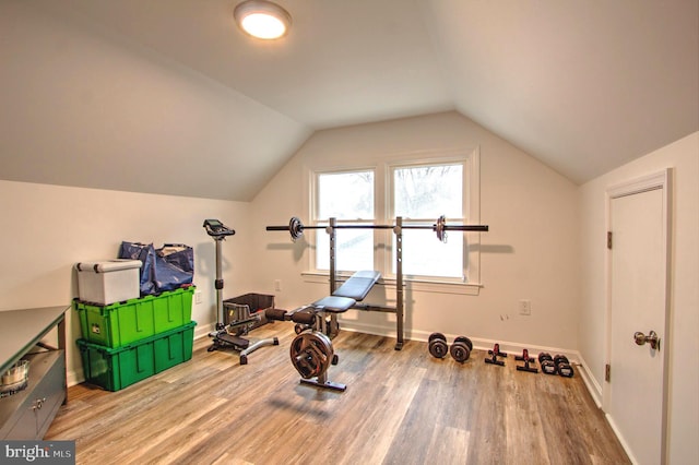 workout room featuring vaulted ceiling, wood finished floors, and baseboards