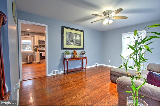 sitting room featuring baseboards, visible vents, ceiling fan, and wood finished floors