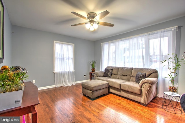 living room featuring hardwood / wood-style floors, a ceiling fan, and baseboards