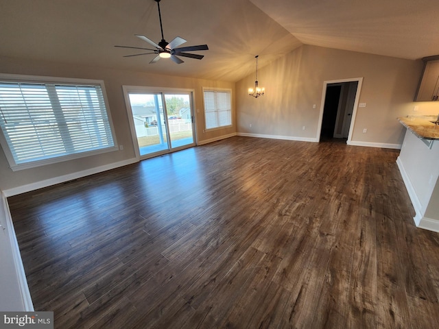 unfurnished living room featuring baseboards, vaulted ceiling, dark wood-type flooring, and ceiling fan with notable chandelier