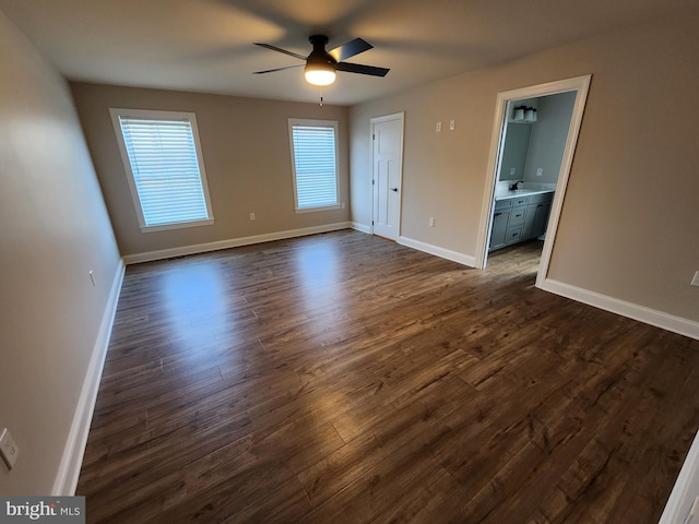 unfurnished bedroom with ceiling fan, baseboards, dark wood finished floors, and a sink