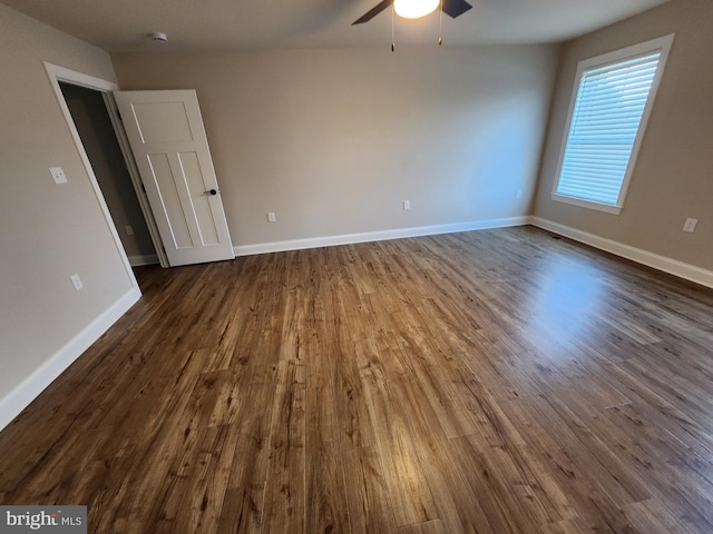 empty room with ceiling fan, dark wood-type flooring, and baseboards