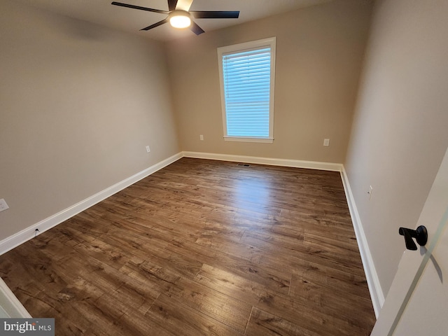 unfurnished room featuring dark wood finished floors, a ceiling fan, and baseboards