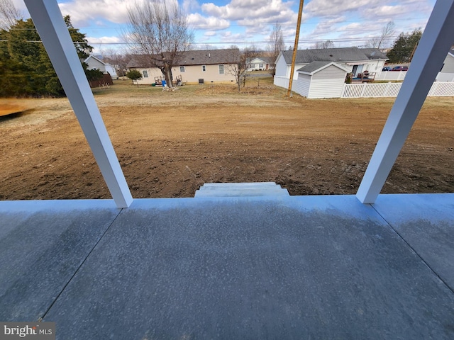 view of yard featuring an outbuilding, a storage unit, fence, and a residential view