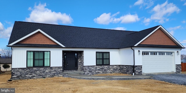 view of front facade featuring stone siding, an attached garage, and driveway