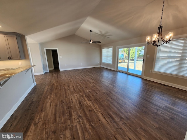 unfurnished living room with visible vents, dark wood-type flooring, vaulted ceiling, baseboards, and ceiling fan with notable chandelier