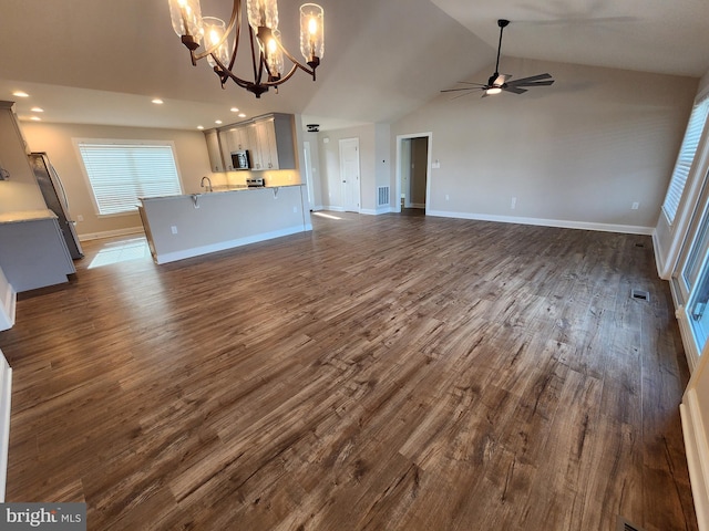 unfurnished living room featuring baseboards, dark wood-style floors, ceiling fan with notable chandelier, vaulted ceiling, and recessed lighting