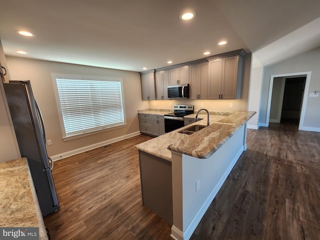 kitchen with dark wood-style flooring, gray cabinetry, appliances with stainless steel finishes, a sink, and light stone countertops