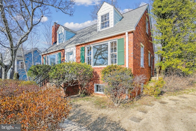 view of front of home with brick siding and a chimney