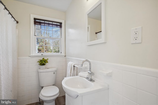 bathroom with toilet, tile walls, and wainscoting