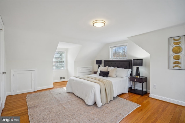 bedroom with multiple windows, visible vents, and wood finished floors