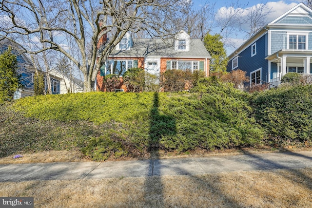 new england style home with brick siding and roof with shingles