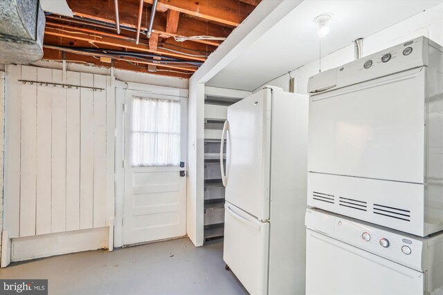 kitchen with stacked washer and dryer, freestanding refrigerator, and concrete floors