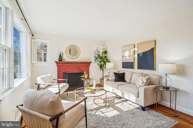 living room featuring a brick fireplace, wood finished floors, and baseboards