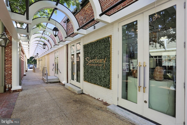 view of property exterior featuring brick siding, a patio area, and french doors