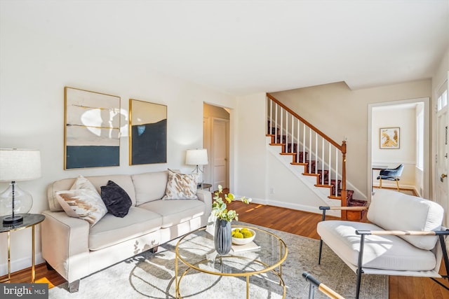 living room featuring stairs, baseboards, and wood finished floors