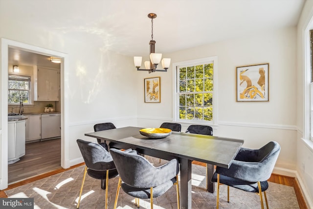 dining area featuring a healthy amount of sunlight, light wood finished floors, and a notable chandelier