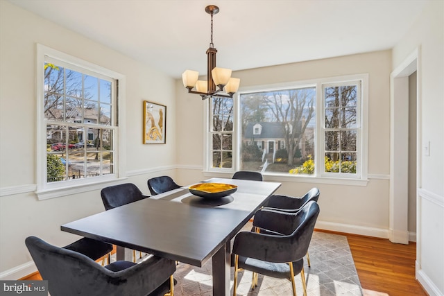 dining area with a chandelier, wood finished floors, and baseboards