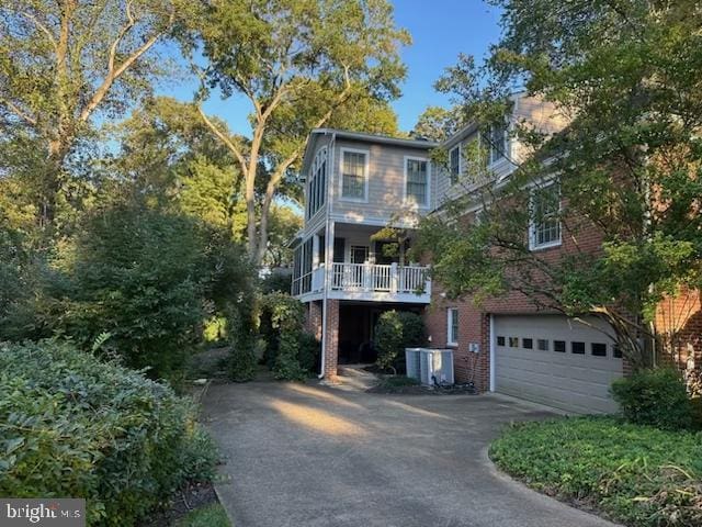 exterior space with driveway, an attached garage, central AC, and brick siding