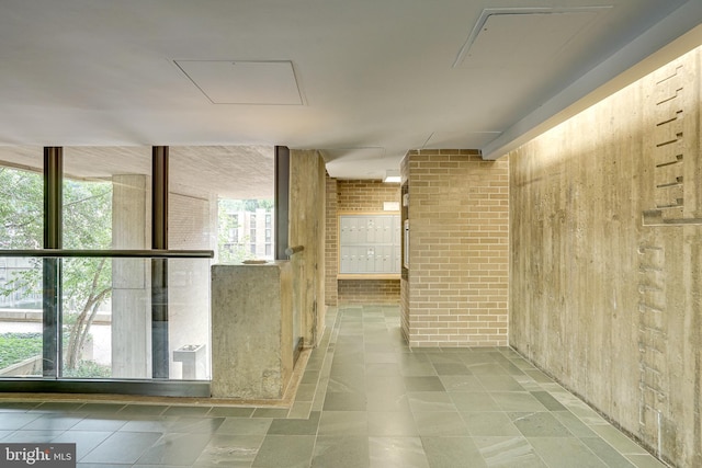 hallway featuring a wall of windows, brick wall, and mail area